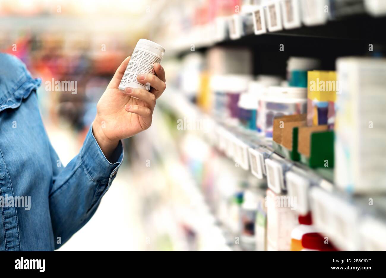 Kunde in Apotheke mit Arzneiflasche. Frau, die den Etikettentext über medizinische Informationen oder Nebenwirkungen im Drogengeschäft liest. Patienteneinkäufe. Stockfoto
