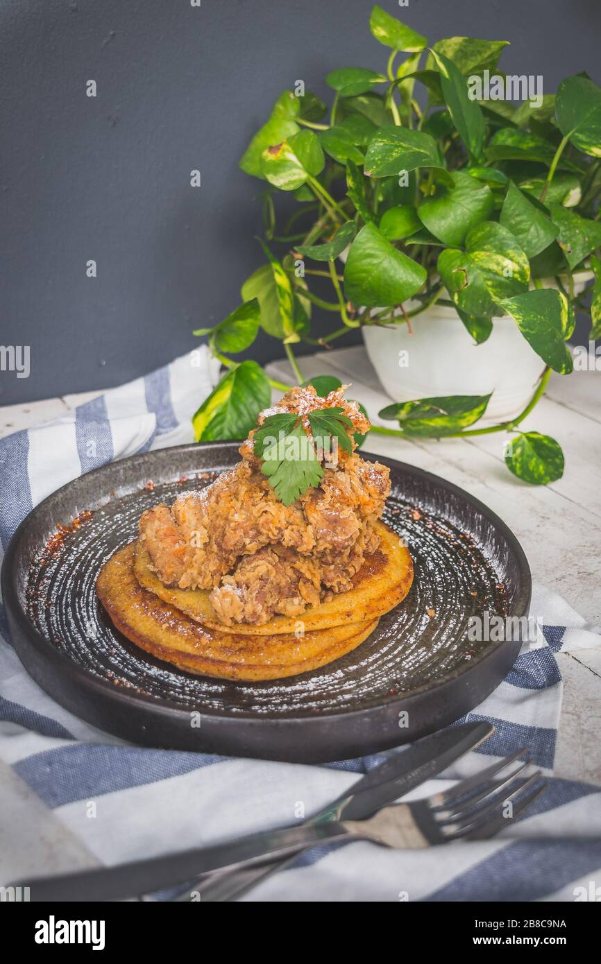 Gebratenes Huhn auf hausgemachten Buttermilchpfannkuchen, serviert mit Chili-Ahorn Stockfoto