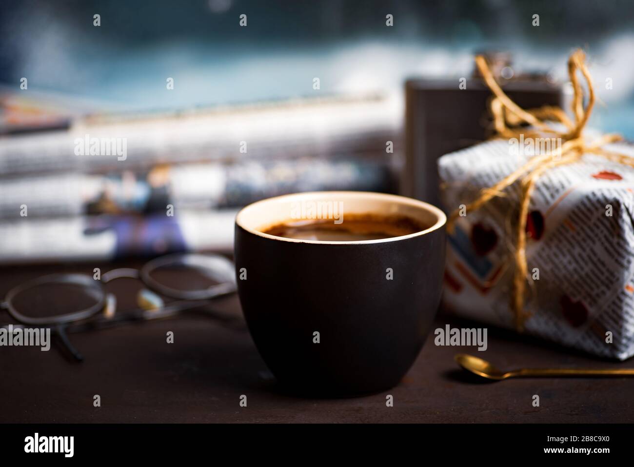Tasse Kaffee mit Lesematerial am Fenster zu Hause Stockfoto