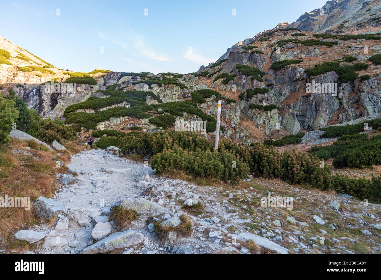 Herbstmorgen im Tal der Dolina Mlynicka in der Nähe des Wodopad-Skok-Wasserfalls in der Slowakei mit Wanderweg, Wodopad-Skok-Wasserfall und klarem Himmel Stockfoto