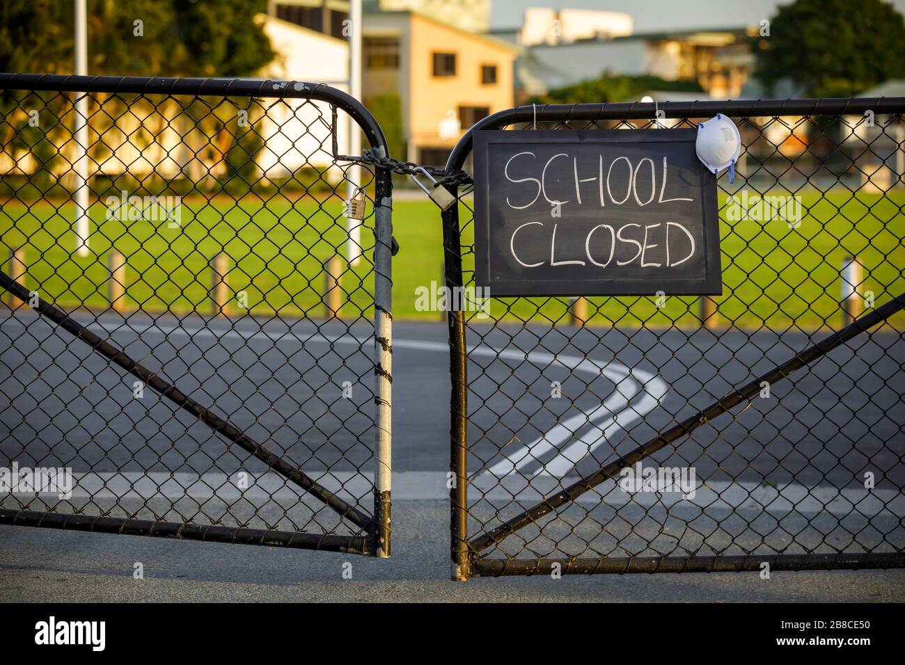 Geschlossenes Schild mit Schutzmaske, die an einem Vorhängeschloss hängt, geschlossenes Schulkonzept oder Shutdown-Konzept inmitten von Coronavirus Ängsten und Panik wegen ansteckender Virusverbreitung des Pandemie-Ausbruchs Stockfoto