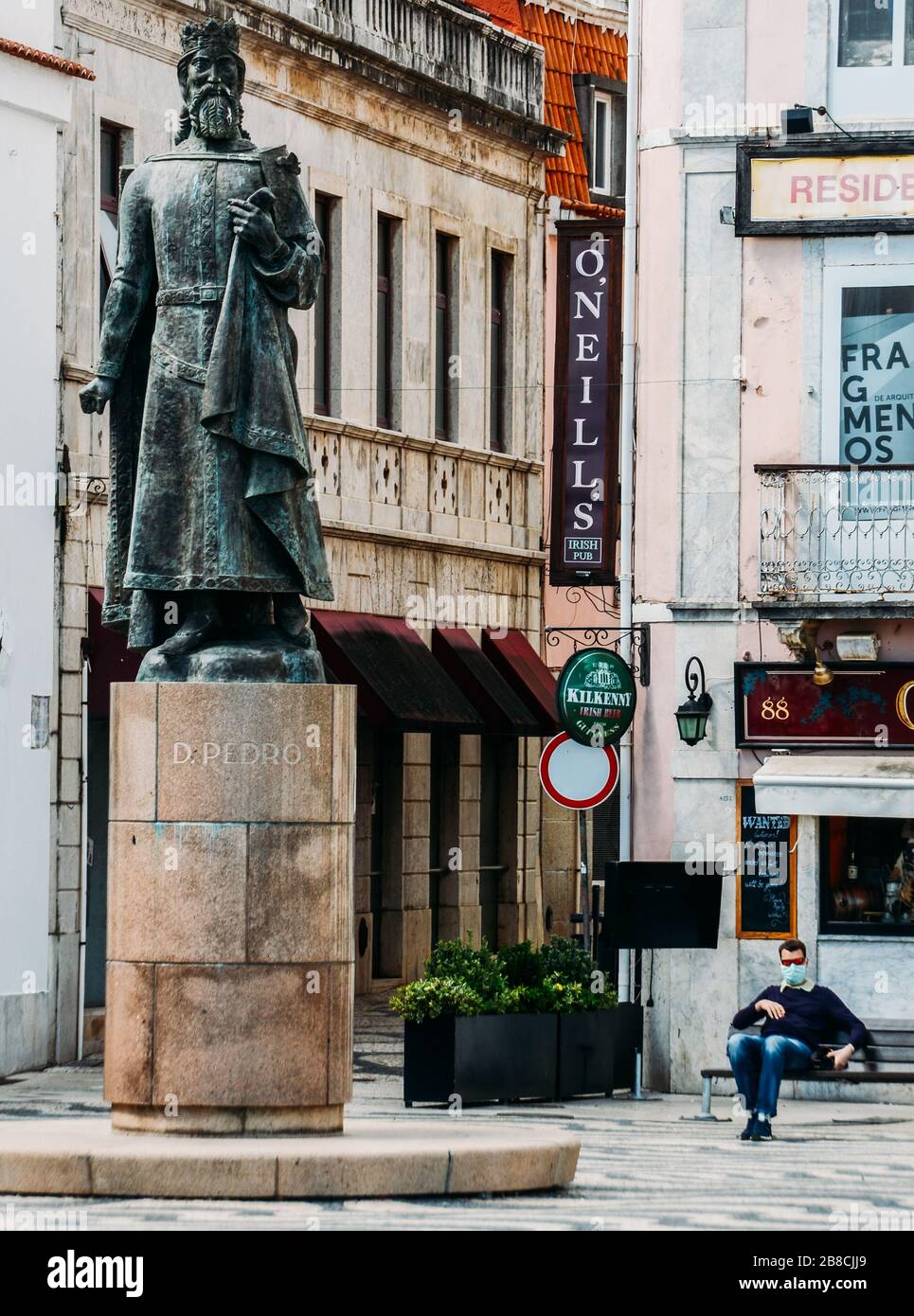 Cascais, Portugal - 21. März 2020: Statue von Don Pedro in Cascais in Portugal mit Mann, der Gesichtsmaske im Hintergrund während der Covid-19-Epidemie trägt Stockfoto