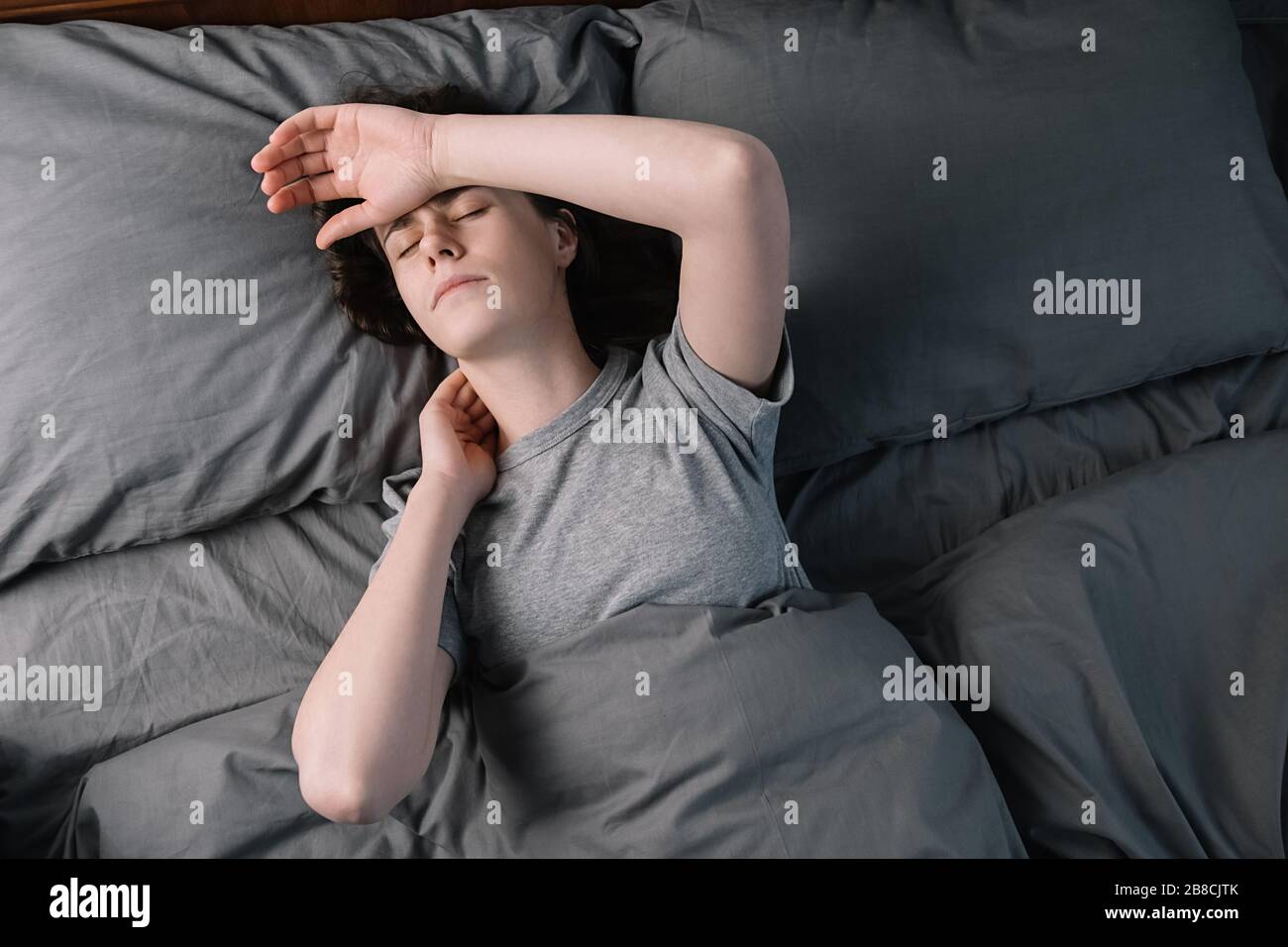 Unglücklich nachdenkliche junge Frau, die Hände auf der Stirn hält, sich traurig einsam liegend im Bett allein versuchen zu schlafen, denken an Problem, Ängste Stockfoto
