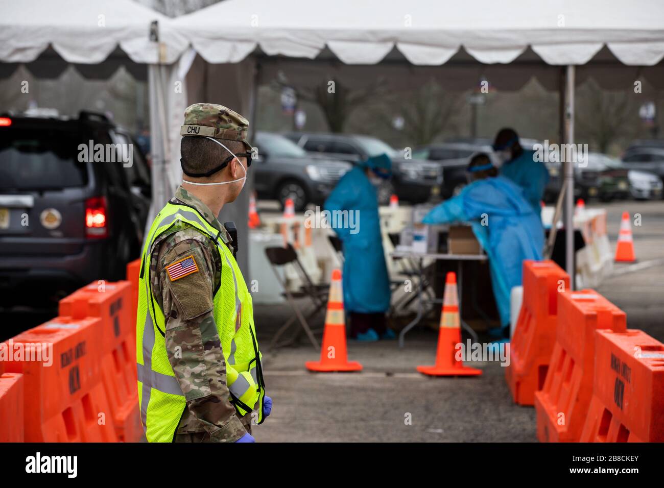 Paramus, NJ, USA. März 2020. Nationalgarde Der New Jersey Army Sgt. Albert Chu, Soldat bei der 508th Military Police Company, leitet den Verkehr an einem COVID-19-gemeinschaftsbasierten Teststandort am Bergen Community College in Paramus, New Jersey, am 20. März 2020. Der in Partnerschaft mit der Federal Emergency Management Agency (FEMA) eingerichtete Teststandort war mit dem Gesundheitsministerium von New Jersey, der Staatspolizei von New Jersey und der Nationalgarde von New Jersey besetzt. Das Drive-Thru-Testzentrum ist sieben Tage pro Woche geöffnet, von 8:00 Uhr bis 16:00 Uhr. Credit: UPI/Alamy Live News Stockfoto