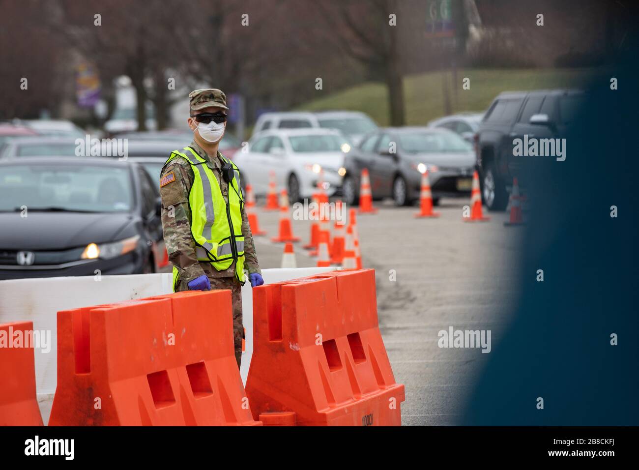 Paramus, NJ, USA. März 2020. Nationalgarde Der New Jersey Army Sgt. Albert Chu, Soldat bei der 508th Military Police Company, leitet den Verkehr an einem COVID-19-gemeinschaftsbasierten Teststandort am Bergen Community College in Paramus, New Jersey, am 20. März 2020. Der in Partnerschaft mit der Federal Emergency Management Agency (FEMA) eingerichtete Teststandort war mit dem Gesundheitsministerium von New Jersey, der Staatspolizei von New Jersey und der Nationalgarde von New Jersey besetzt. Das Drive-Thru-Testzentrum ist sieben Tage pro Woche geöffnet, von 8:00 Uhr bis 16:00 Uhr. Credit: UPI/Alamy Live News Stockfoto