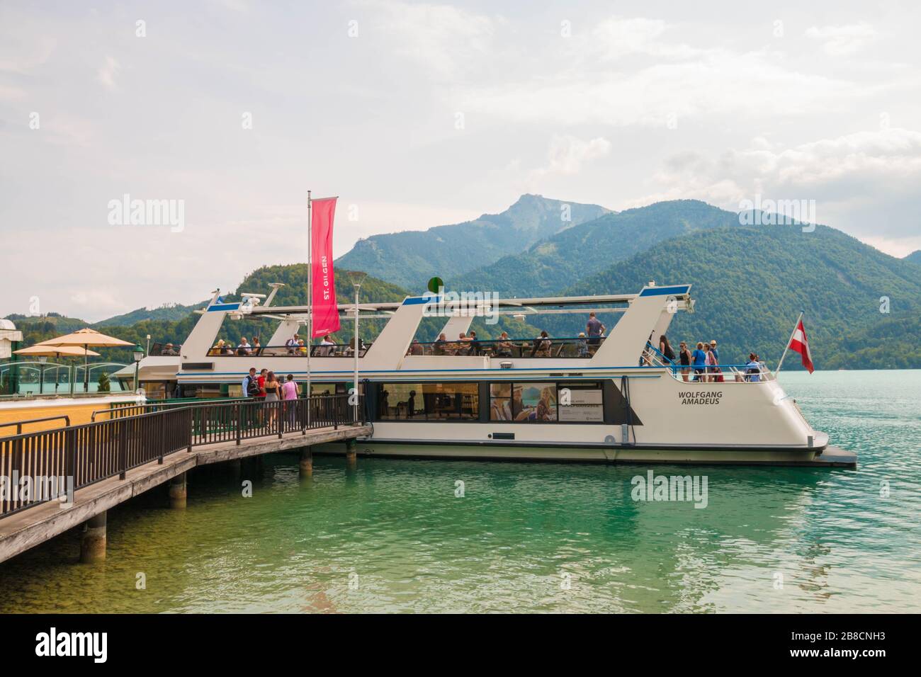 St. Gilgen, Österreich - 27. Juli 2019: Menschen, die am Pier in der Alpenstadt am Wolfgangsee mit dem Boot "Wolfgang Amadeus" einsteigen. Stockfoto