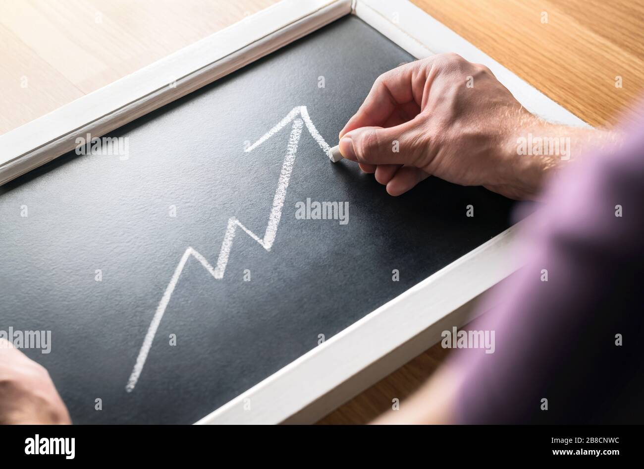 Wirtschaftswachstum. Prognose des steigenden Umsatzes oder Gewinns in der Wirtschaft. Bericht über die Finanzen. Erfolgreicher Business man zeichnet zunehmend Graph auf dem Schwarzen Brett. Stockfoto