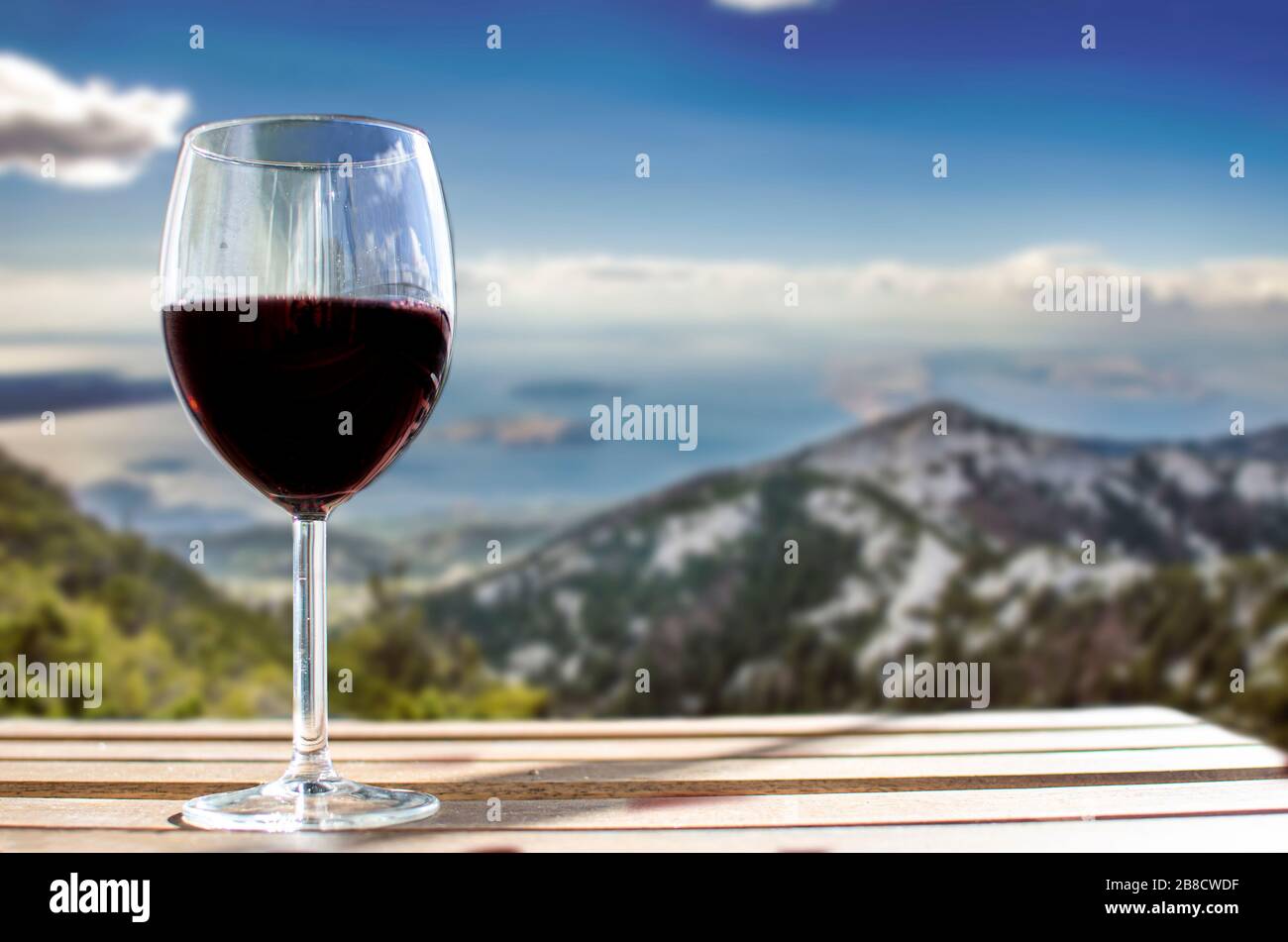 Glas Wein auf den Velebit-Bergen verschwimmen in Kroatien den Hintergrund. Sonniger Blick auf ein Glas Rotwein mit Blick auf die Berge, Kroatien Stockfoto