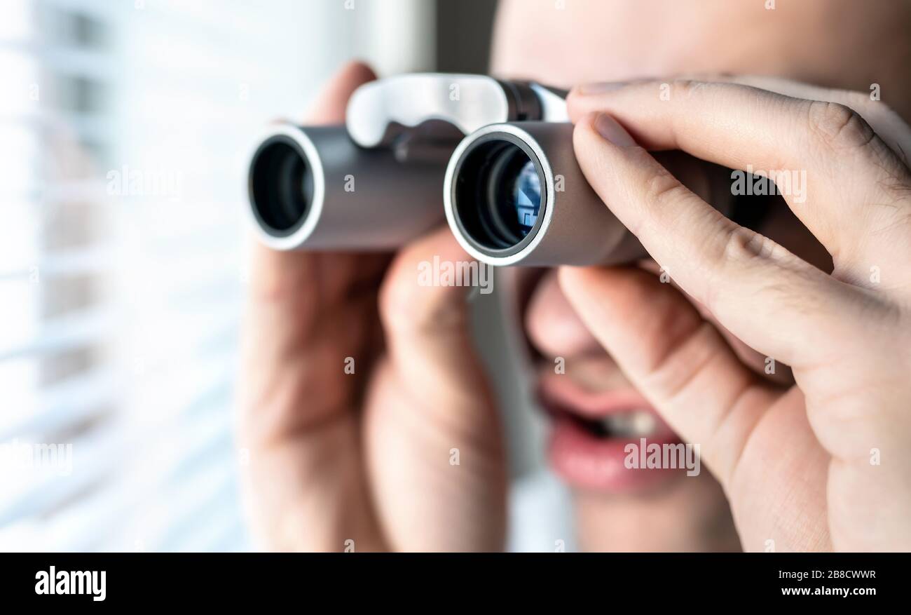 Neugieriger Nachbar oder Stalker mit Fernglas. Lustiger verrückter Mann, der die Leute anstarrt. Neugieriger Kerl, der auf das Fenster blickt. Albern Gesicht. Snooping und Suche. Stockfoto