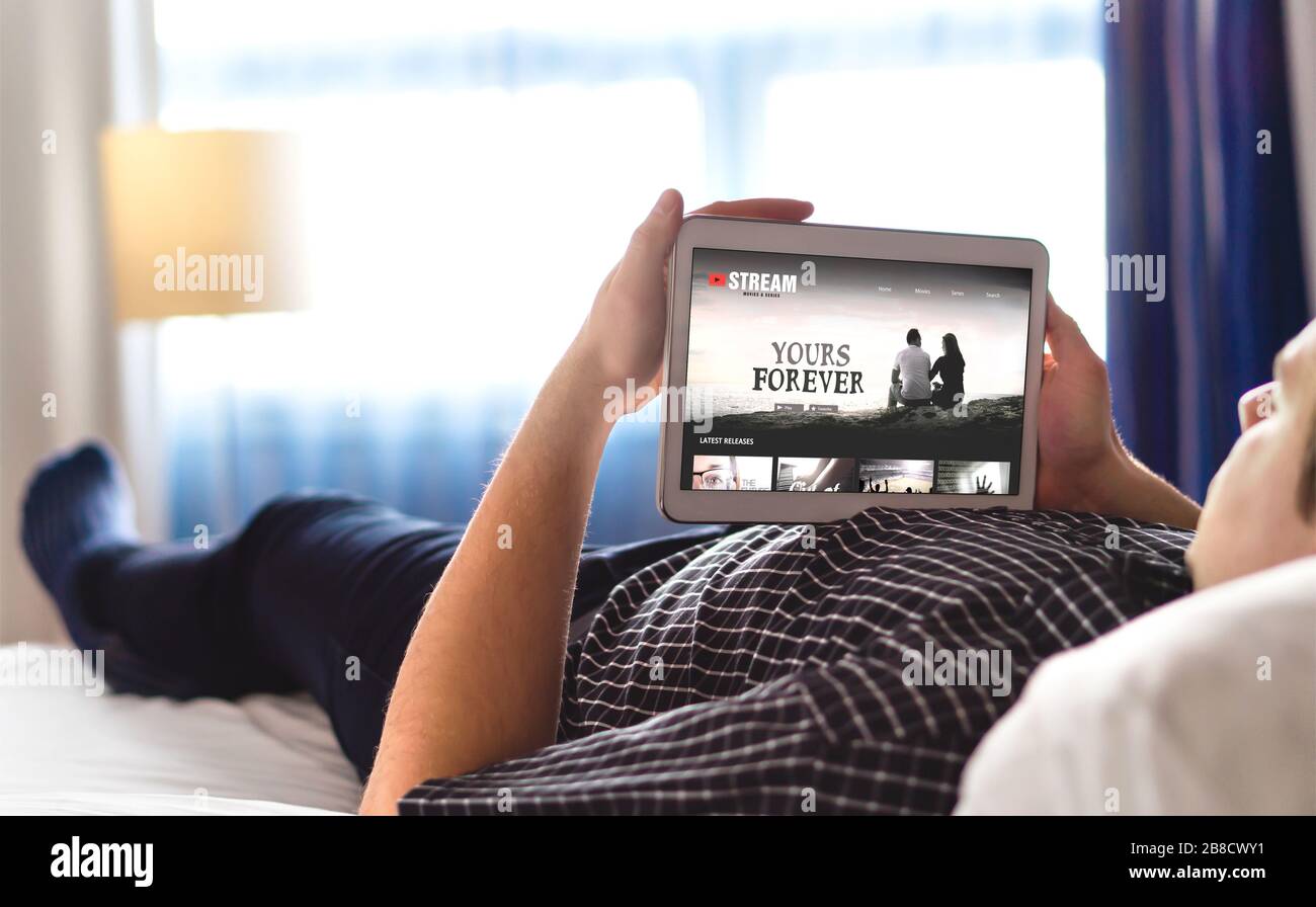 Film-, Video- und Online-Streaming-Service im Tablet. Der Mann wählt und sieht digitale Filme mit einem intelligenten Gerät an. Entspannende Person. TV-Netzwerk Internet. Stockfoto