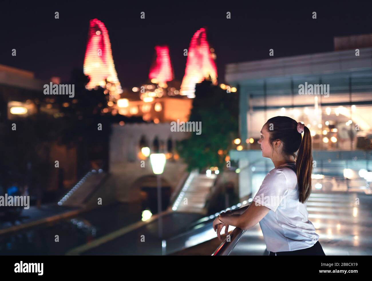 Frau in Baku nachts mit Blick auf die Flame Towers. Touristen in Aserbaidschan im Urlaub. Erkunden Sie die Hauptstadt und besuchen Sie sie. Stockfoto