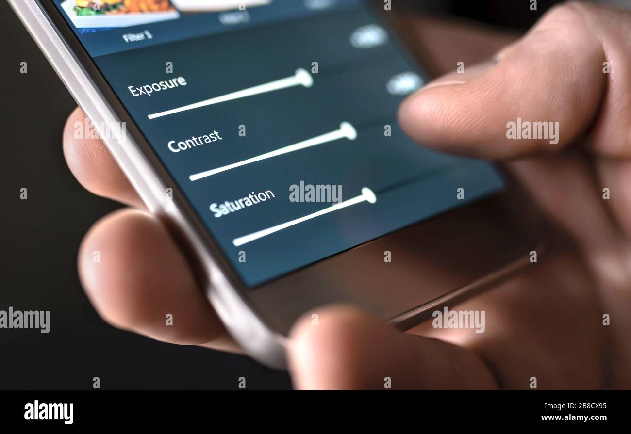 Fotobearbeitung mit Handy und Smart App. Man-Einstellschieber. Bildbearbeitung, Manipulation, Verbesserung oder Verbesserung mit Smartphone. Stockfoto
