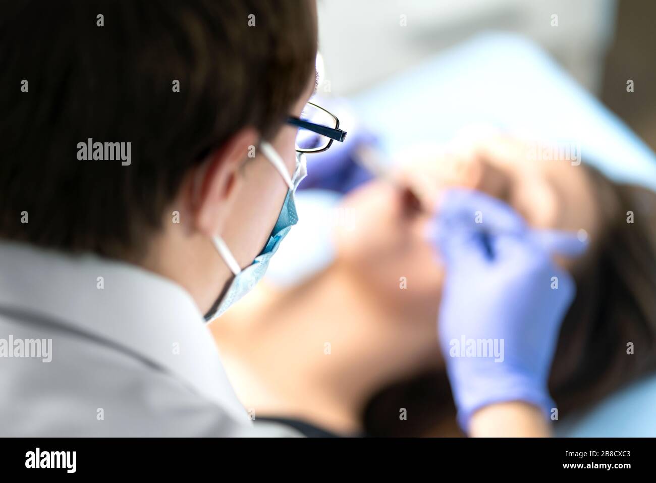 Zahnärztin oder Zahnarzthelferin in Betrieb mit dem Patienten. Frau mit Kalkül oder Karies. Mundarzt entfernt Weisheitszähne. Zahnmedizin. Stockfoto