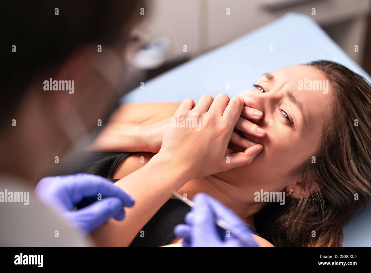 Angst vor Zahnärzten oder Angst vor Ärzten. Erschrockter und nervöser Patient im Krankenhaus. Fehlverhalten oder gefälschtes Ärztekonzept. Frau mit der Kobie verärgert. Stockfoto