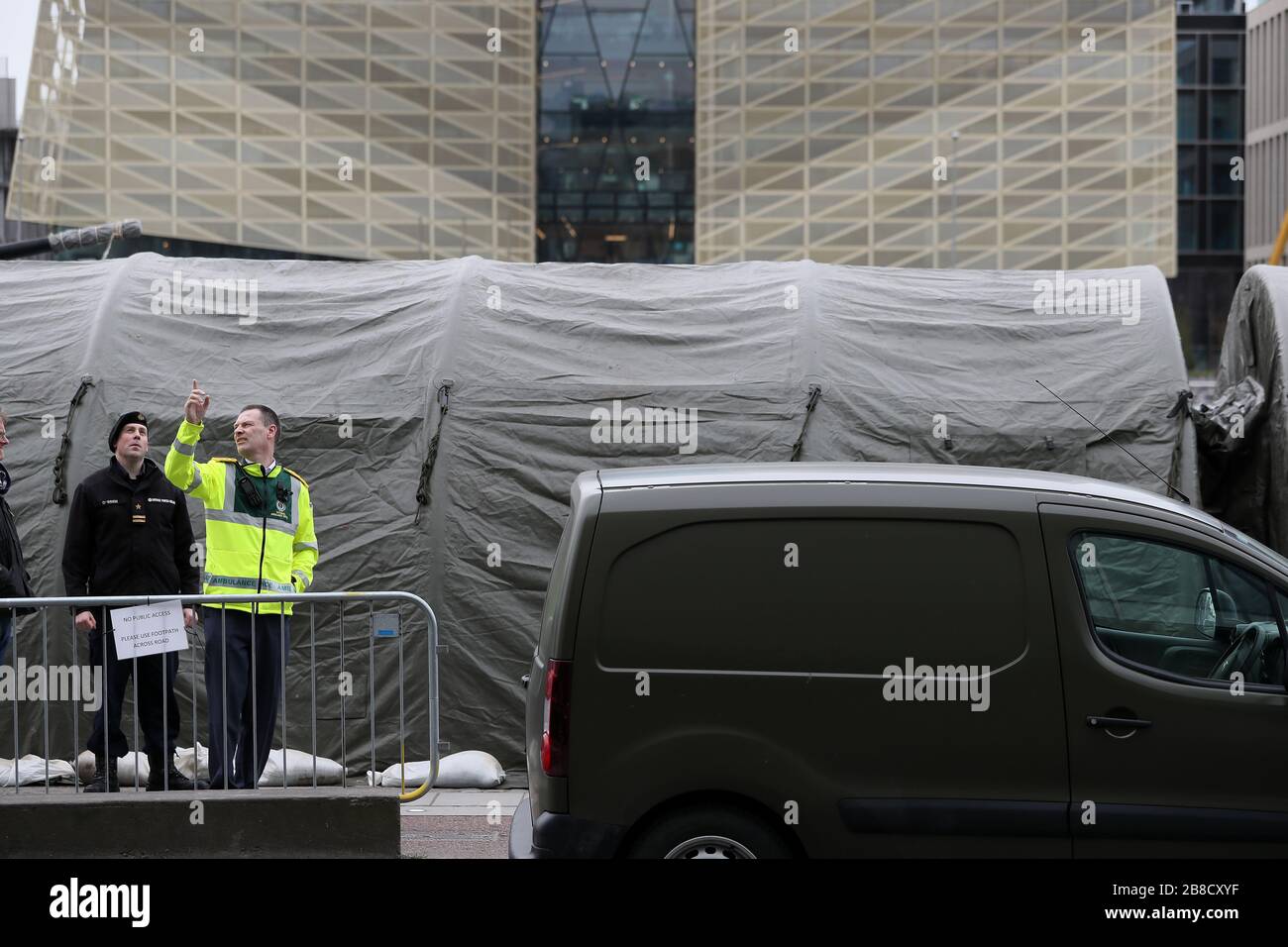 Ein Mitglied des nationalen Ambulanzdienstes mit Mitgliedern der Verteidigungskräfte am Quay von Sir John Rogerson in Dublin als Zelte der Verteidigungskräfte wurden neben dem L Samuel Beckett vor dem Einsatz als Testzentrum für Covid-19 eingerichtet. Stockfoto