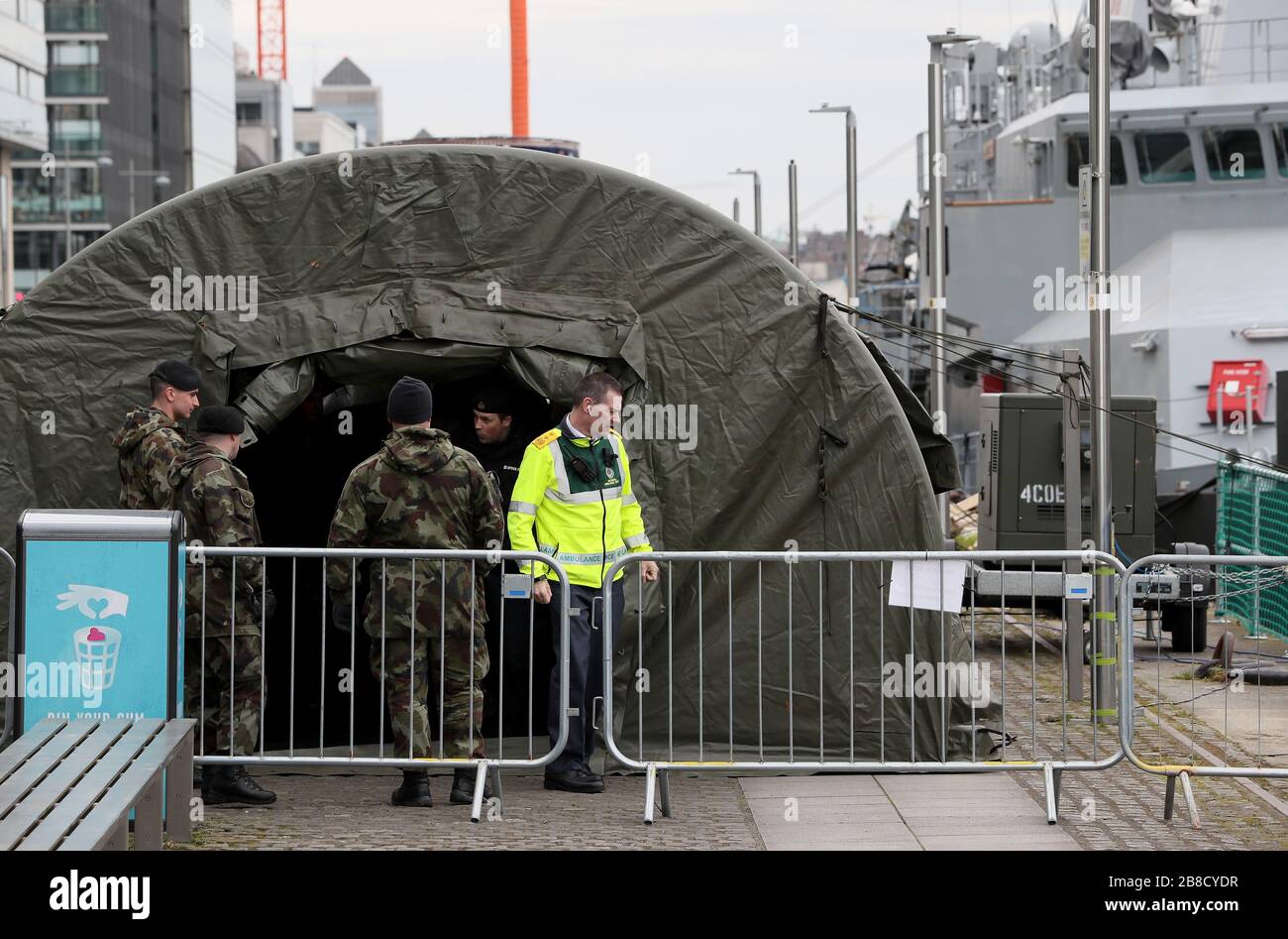 Ein Mitglied des nationalen Ambulanzdienstes mit Mitgliedern der Verteidigungskräfte am Quay von Sir John Rogerson in Dublin als Zelte der Verteidigungskräfte wurden neben dem L Samuel Beckett vor dem Einsatz als Testzentrum für Covid-19 eingerichtet. Stockfoto