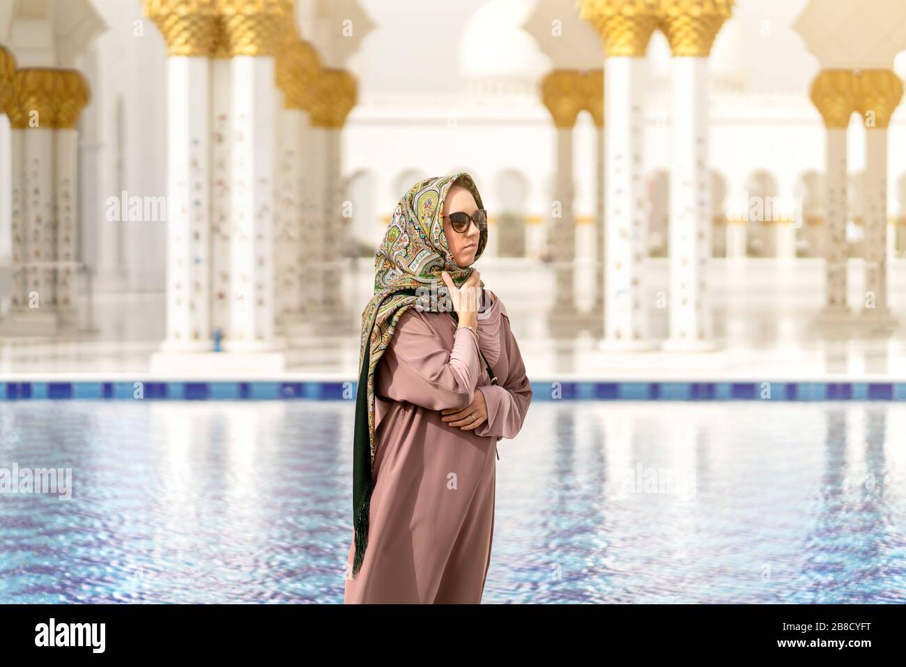 Frau in der großen Moschee von Scheich Zayed vor dem Wasser. Islamisches Dekor. Weibliche Touristin im muslimischen Land. Tourismus, Reisen und Menschen im Urlaub. Stockfoto