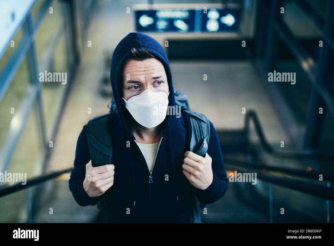 Mann, der Gesichtsmaske auf der Rolltreppe trägt. Themen: Coronavirus und persönlicher Schutz während einer Pandemie. Stockfoto