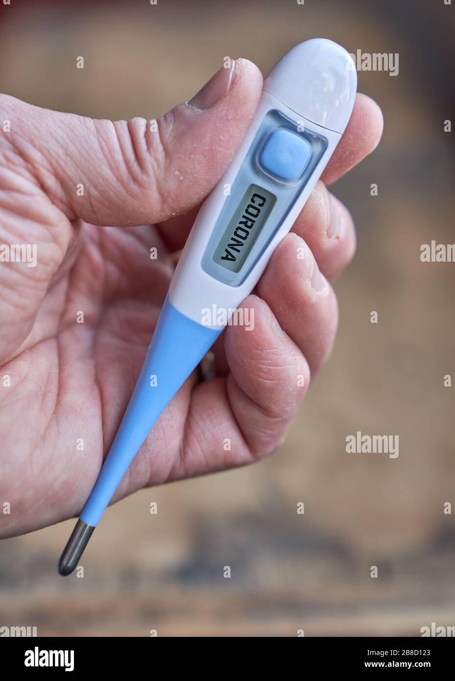 Die männliche Hand hält klinisches Thermometer mit Koronatext auf dem Bildschirm während der globalen Kovid-19- oder Corona-Pandemie Stockfoto