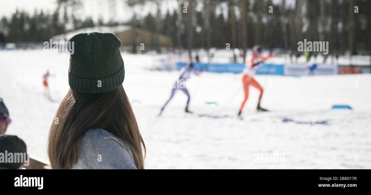 Fan jubelt im Skiwettbewerb. Winter-Weltmeisterschaft-Skiveranstaltung. Frau beobachtet Skilangläufer, die im Stadion gegeneinander antreten. Menge unterstützend. Stockfoto