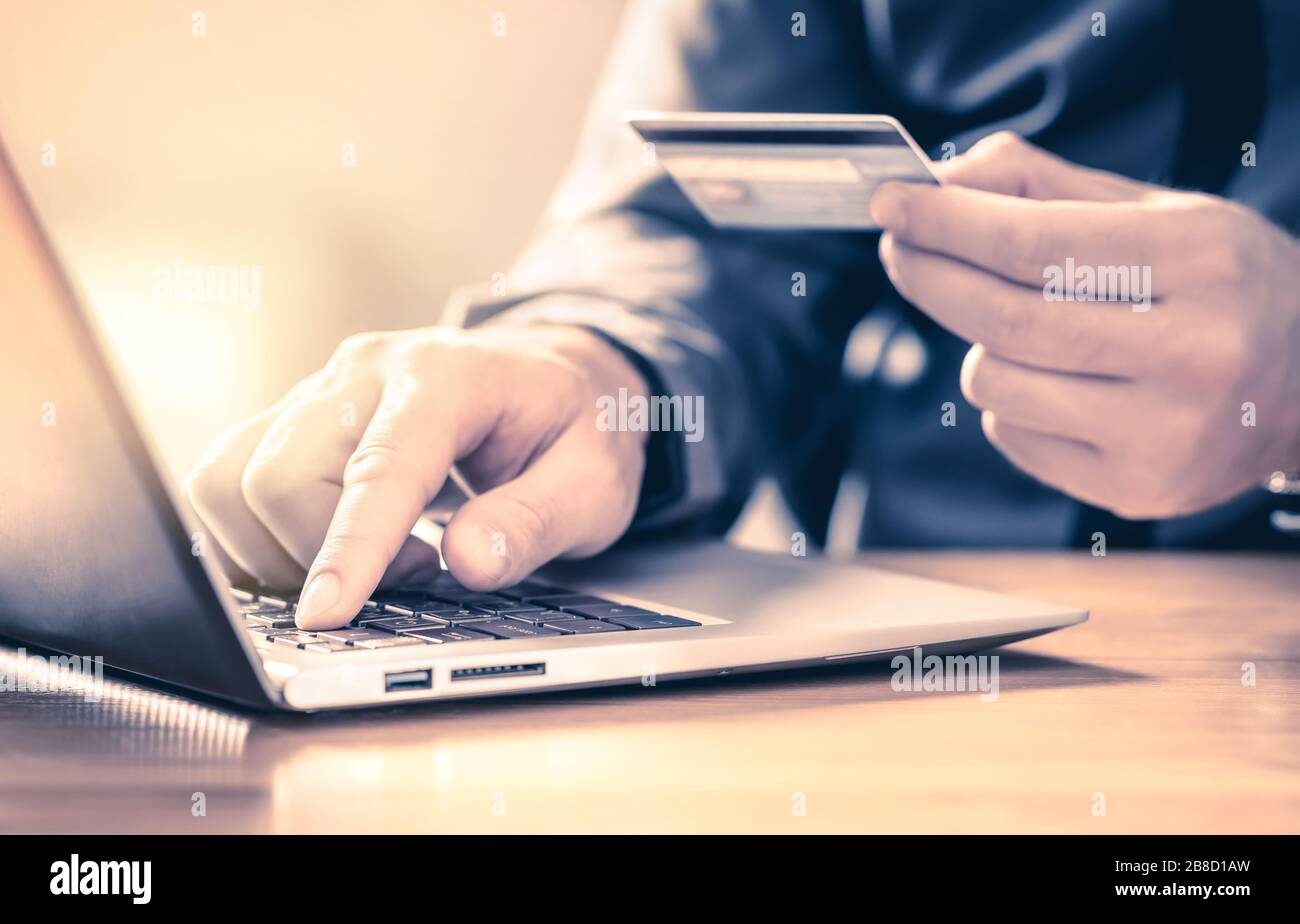 Mann, der mit Kreditkarte und Laptop online bezahlt. Digitaler E-Commerce-Service. Zufriedene Kunden kaufen und bezahlen im Internet mit Computer. Stockfoto