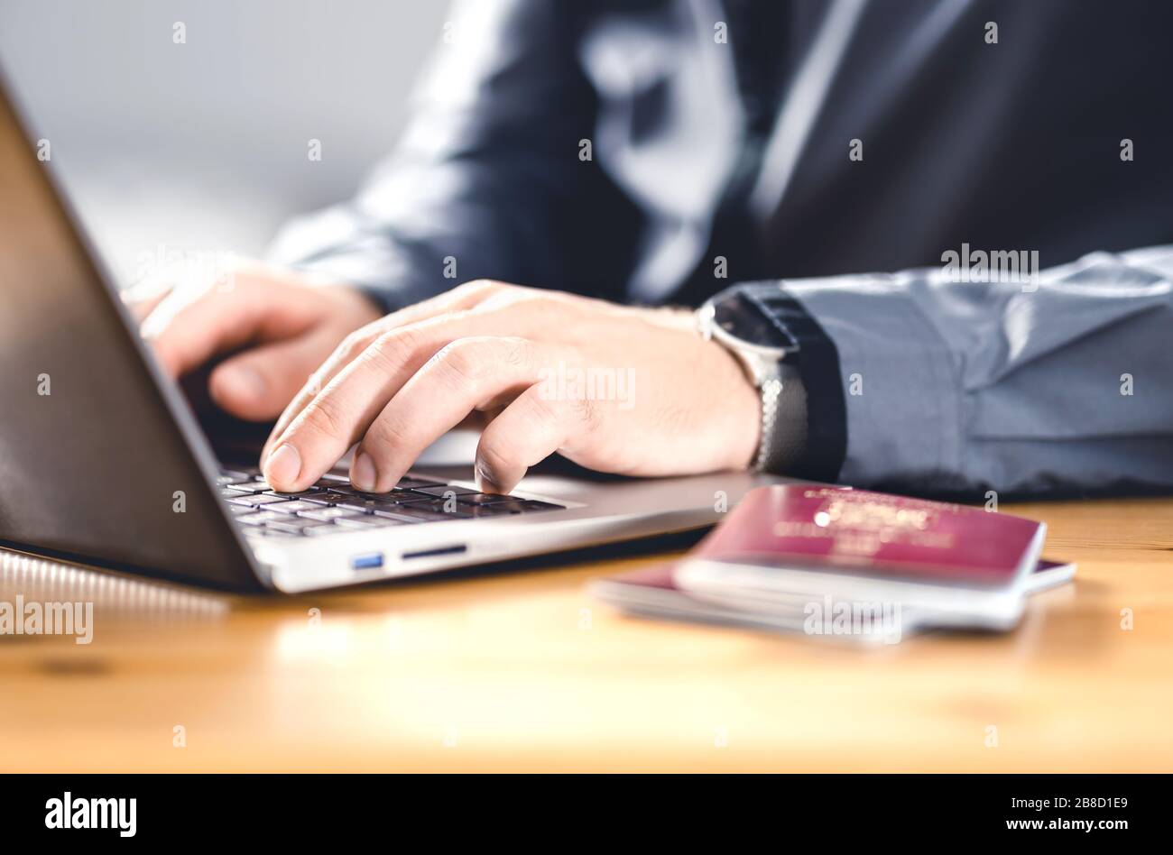 Mann mit Pass und Laptop. Reisedokument und Identifikation. Immigranten, die einen elektronischen Antrag auf Staatsbürgerschaft schreiben. Beantragen Sie ein digitales Visum. Stockfoto