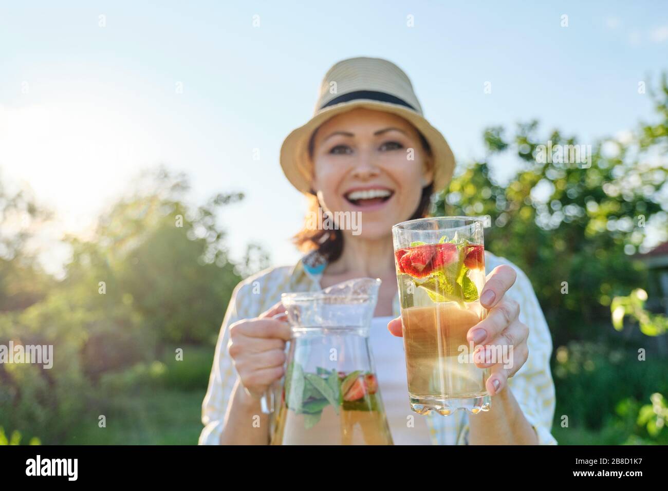 Frühlingssommer-Erfrischungen, Frau in der Natur, die einen Krug mit Erdbeerminze und Zitrone hält, kalte Erfrischungsgetränke, gesunde, hausgemachte Vitamingetränke Stockfoto