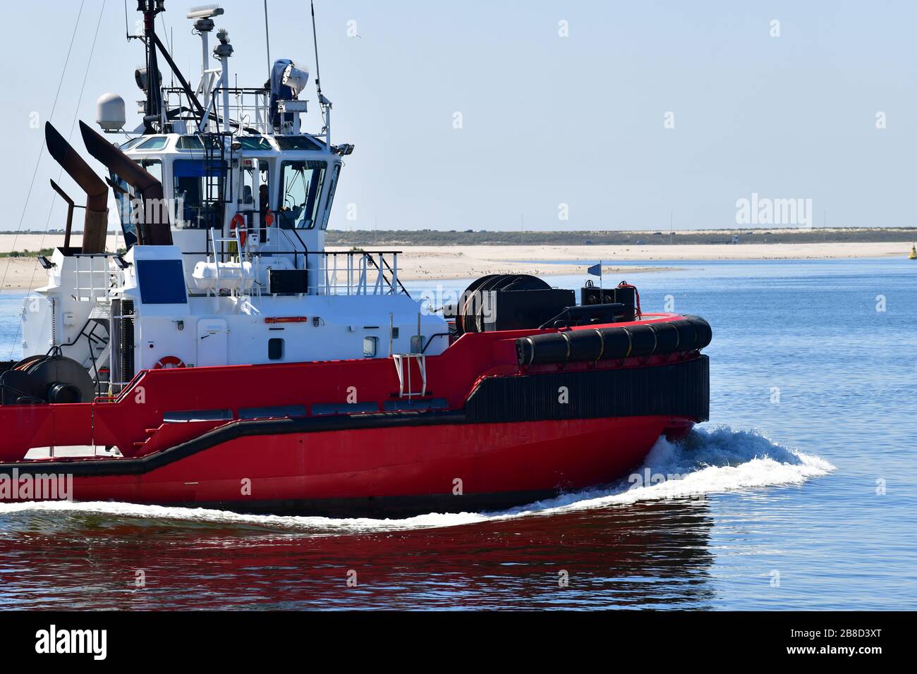 Vor dem Strand liegt eine Schleife in der Nähe des modernen, leuchtend roten Schleppboots im Rotterdamer Hafen Stockfoto