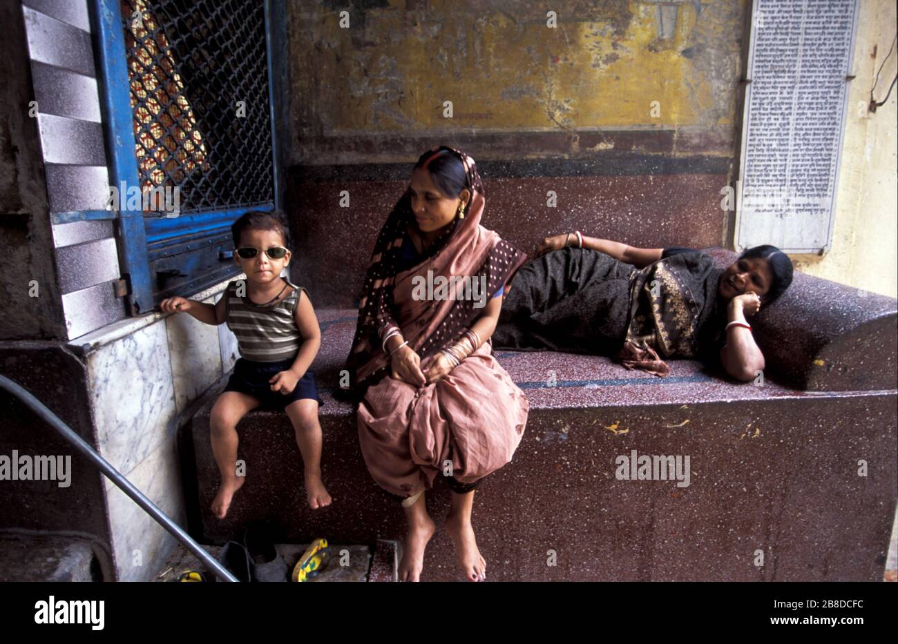 Der Junge trägt Sonnenbrille bei seiner Mutter und seiner Großmutter in einer alten Stadtallee Varanasi, Uttar Pradesh, Indien Stockfoto