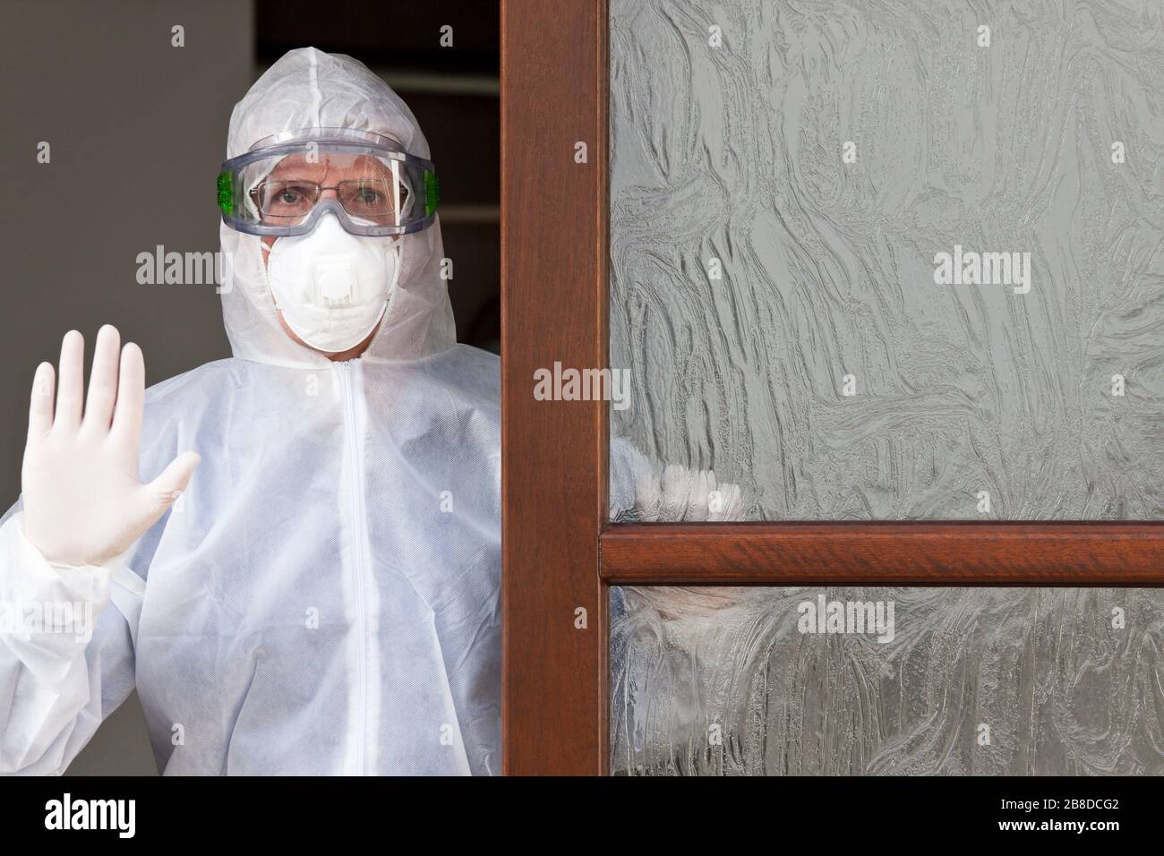 Arzt mit Schutzkleidung an einem Eingang einer Klinik Stockfoto