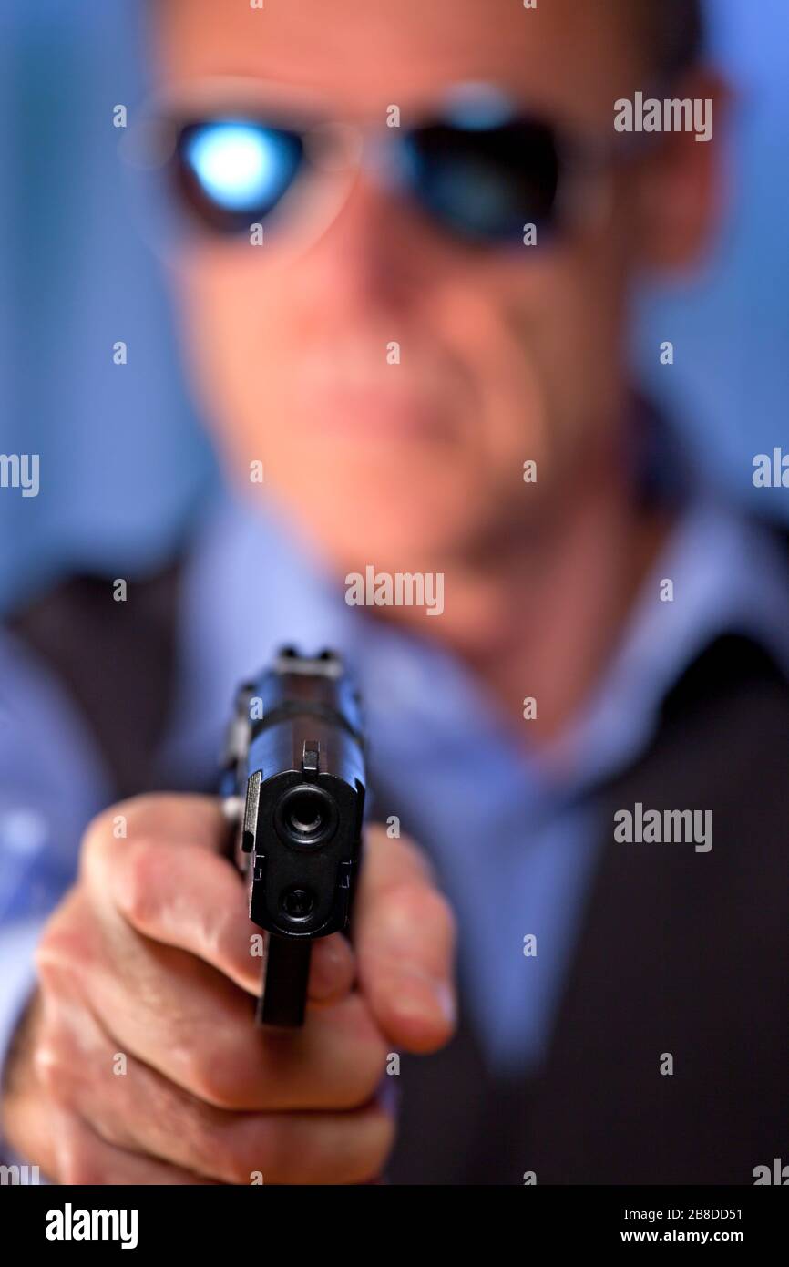 Killer, Mafiaboss oder Gangster, die eine Waffe auf den Zuschauer richten - konzentrieren Sie sich auf den Punkt der Pistole Stockfoto