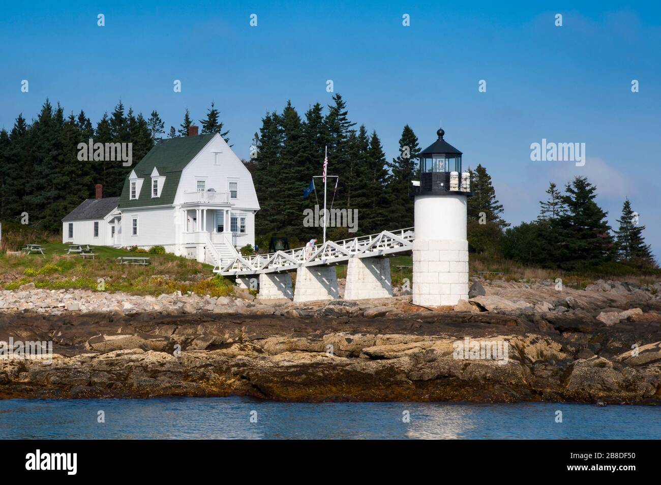 Hafenblick auf den Marshall Point Lighthouse in Port Clyde in Maine entlang des felsigen Ufers. Das Gebiet zieht eine Künstlergemeinschaft an. Stockfoto