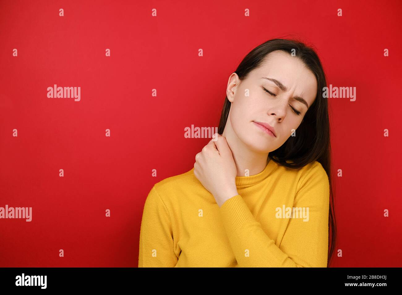 Müde weibliche Gefühl steif Wunde Nackenschmerzen Konzept reiben massieren angespannte Muskeln leiden an Fibromyalgie, hat düsteren Ausdruck, trägt Pullover Stockfoto