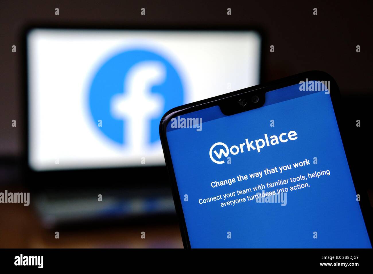 Workplace App auf dem Smartphone und verschwommenes Facebook-Logo auf dem Hintergrund. Workplace ist eine Plattform mit zu Stockfoto