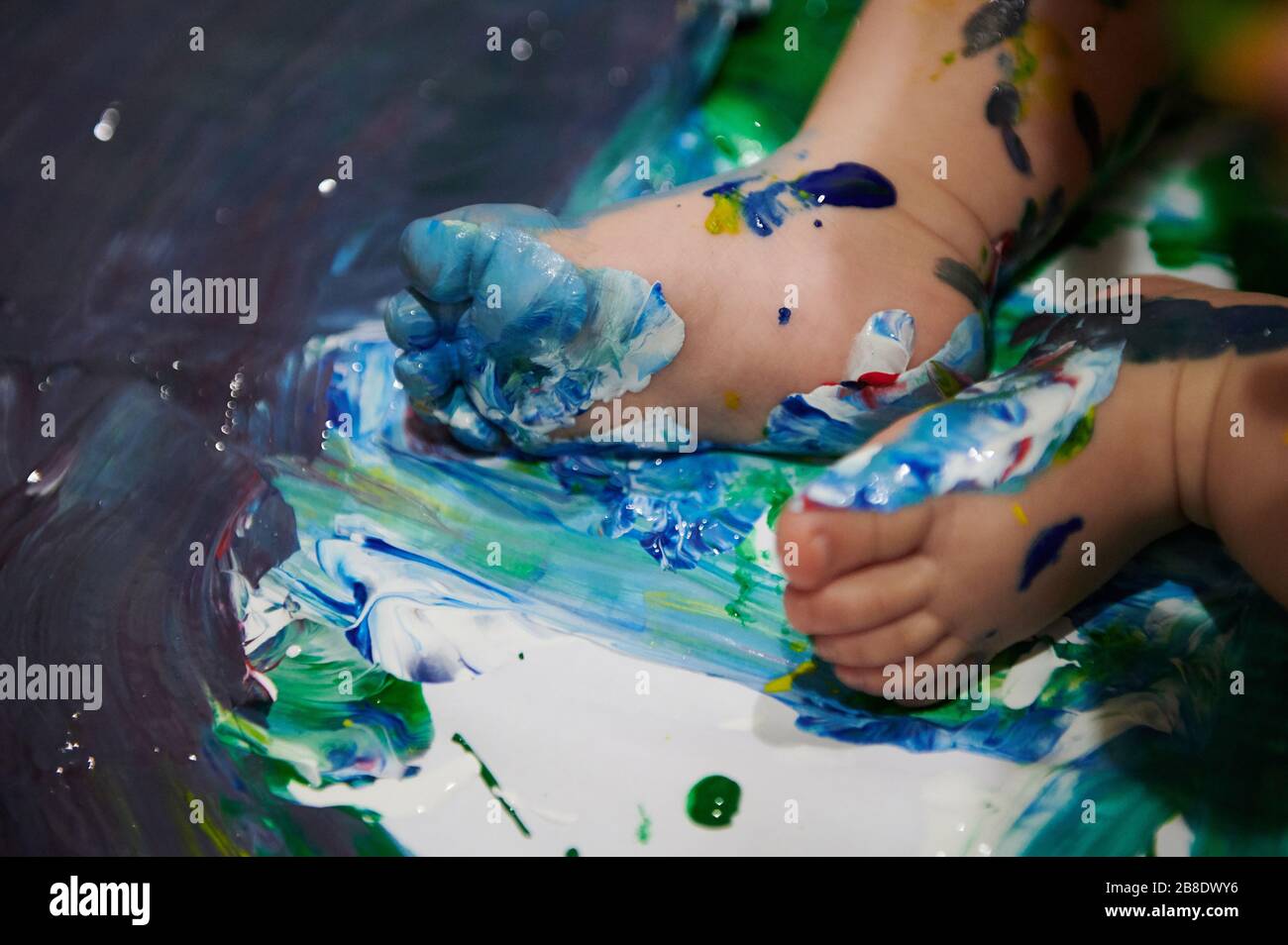 Kleiner Babyfuß schmutzig von nasser Farbe Nahansicht Stockfoto