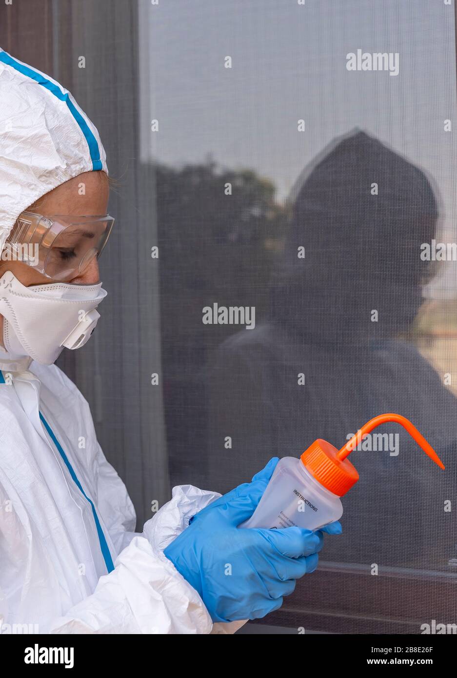 Ein Mitarbeiter des Gesundheitswesens desinfiziert, um mögliche Ansteckungen aus Covid-19-Coronavirus mit einer hydroalkoholischen Lösung zu vermeiden, die vollständig von Overall abgedeckt ist Stockfoto