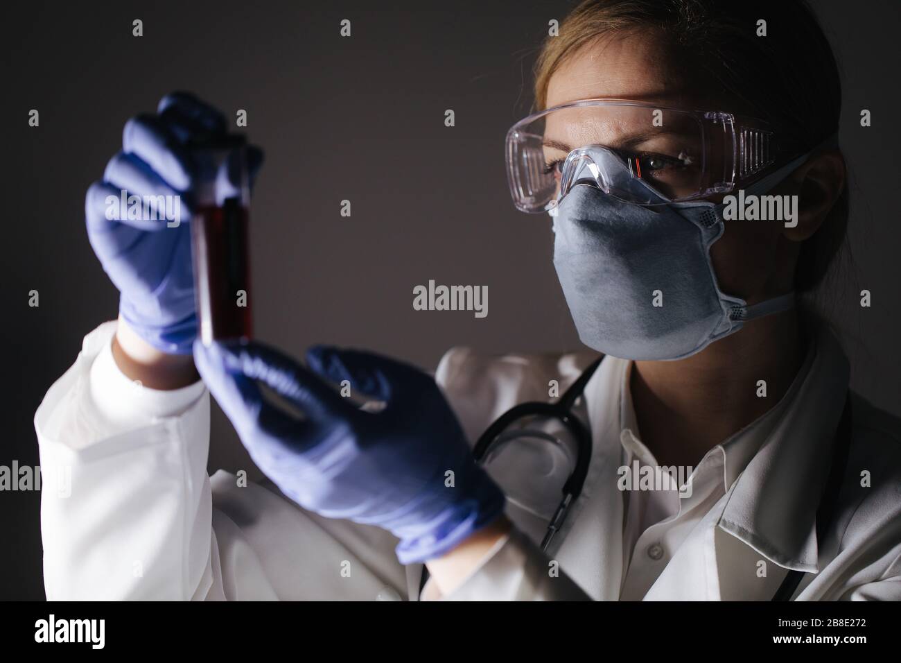 Frau in medizinischen Anzug mit Reagenzglas mit Blutproben Stockfoto