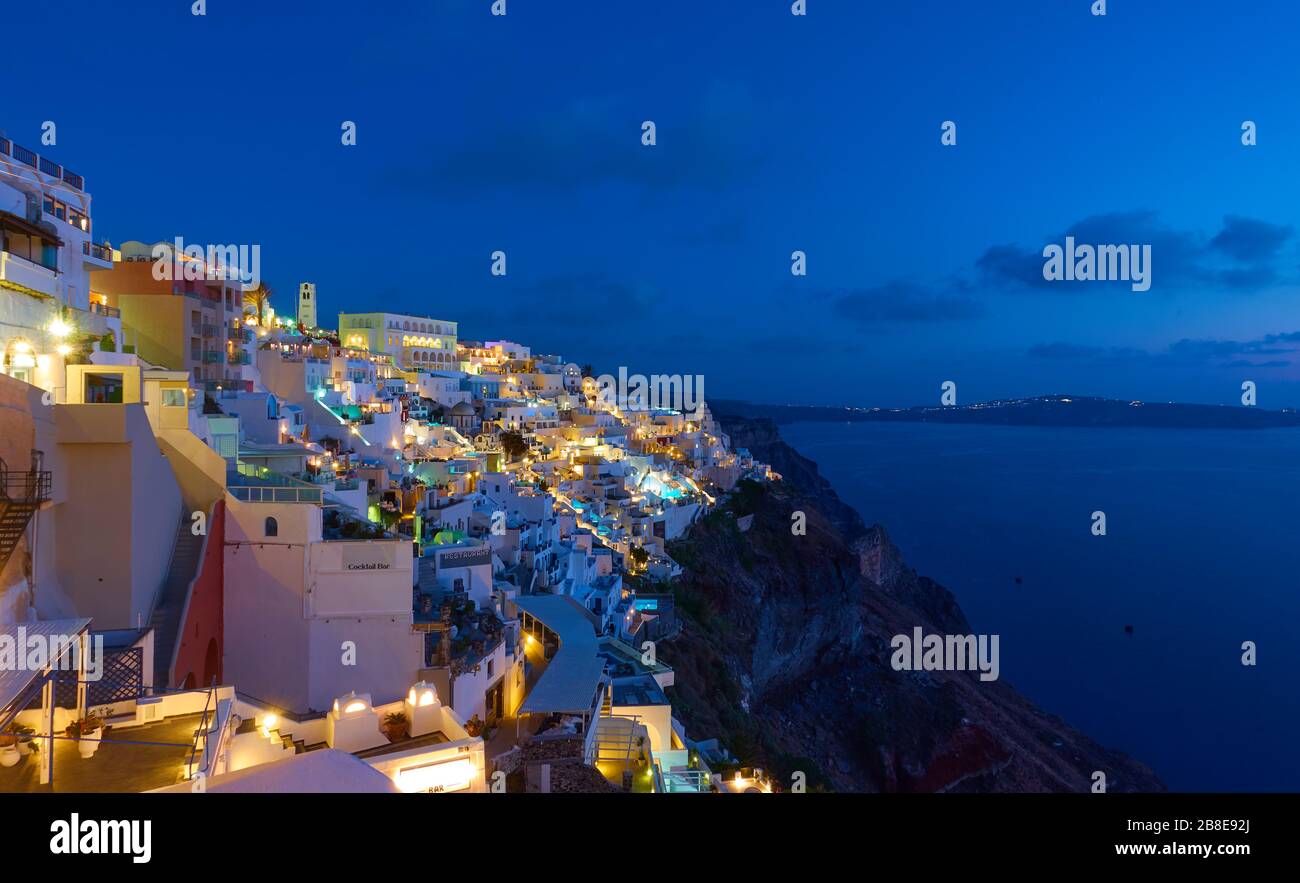 Panoramablick auf die Stadt Thira auf der Insel Santorini, beleuchtet durch die Lichter von Bars, Hotels und Restaurants in der Dämmerung, Griechenland. Griechische Landschaft - Stadtbild Stockfoto