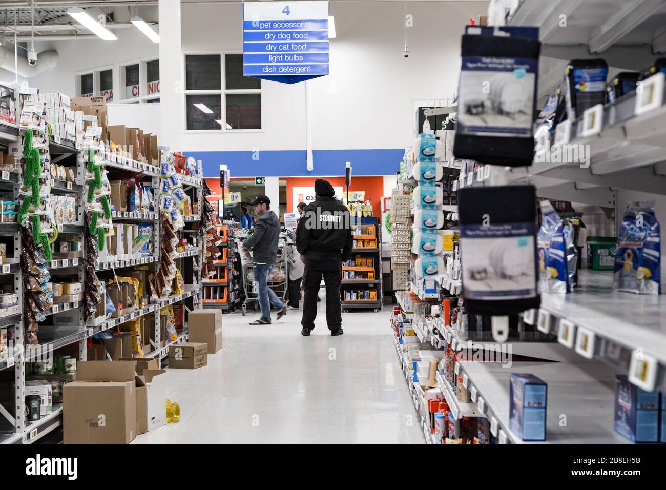 NORTH VANCOUVER, BC, KANADA - MAR 19, 2020: Ein Wachmann beobachtet die Käufer in einem lokalen Supermarkt, der in Erwartung von Lebensmitteln aufhält Stockfoto