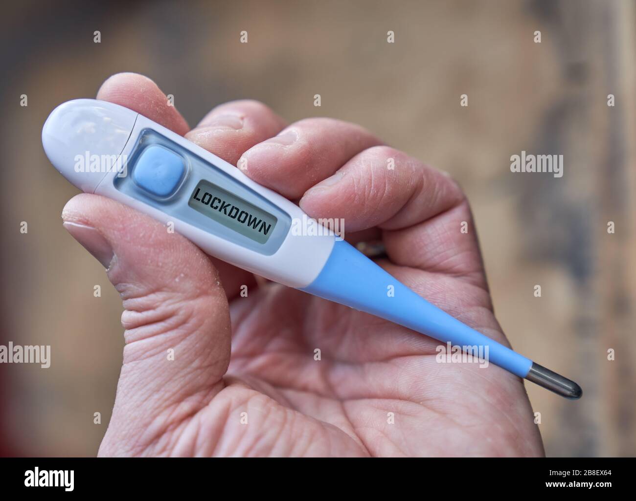 Die männliche Hand hält klinisches Thermometer mit Sperrtext auf dem Bildschirm während der globalen Kovid-19- oder Corona-Pandemie Stockfoto