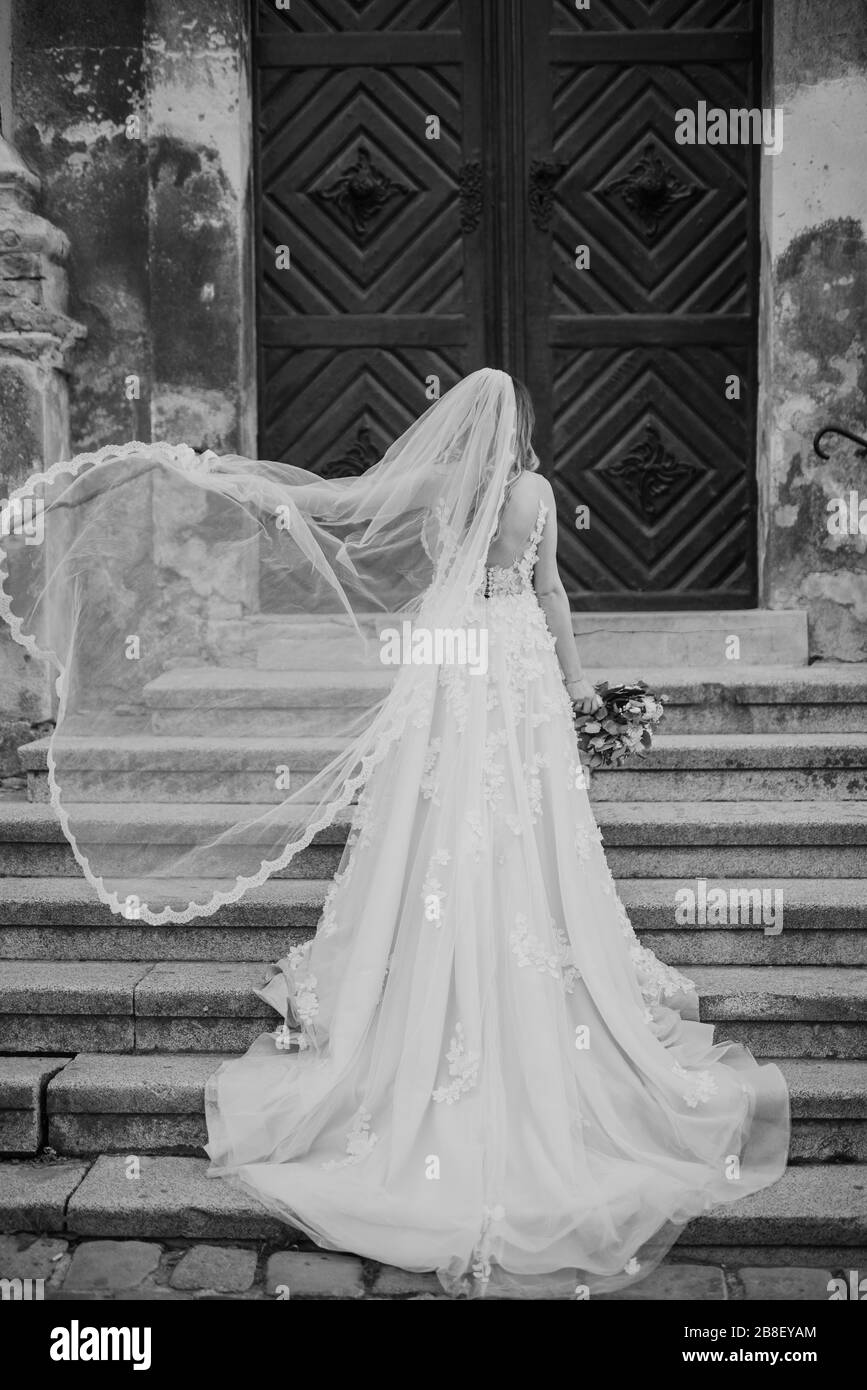 Die Frau in einem schönen Hochzeitskleid und ihrem brautstrauß mit Blumen Stockfoto