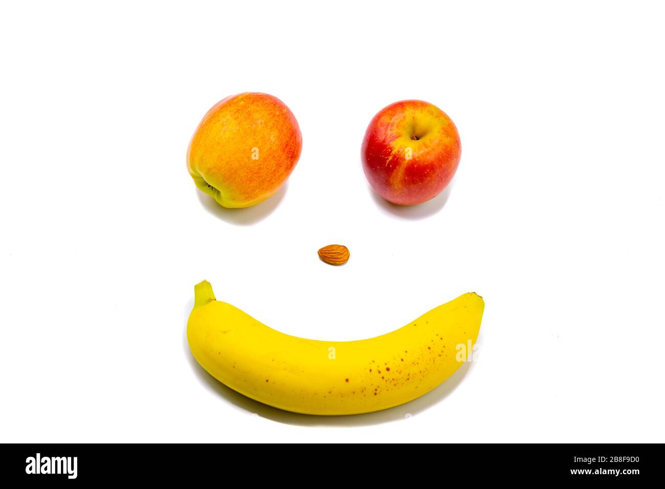 Smiley Gesicht mit Wink mit zwei Äpfeln, einer Mandel und einer Banane Stockfoto