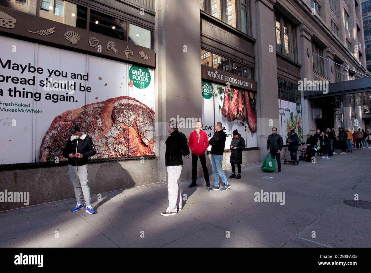 New York City, New York, Vereinigte Staaten. März 2020. Linien bildeten sich, um in den Whole Foods Supermarkt in der Chelsea Nachbarschaft von Manhattan in New York City zu gelangen, da New Yorker neue Realitäten im Zusammenhang mit der Coronavirus Pandemie konfrontierte. Der Store führte eine Richtlinie ein, die Kunden in akzeptablen Abständen online warten ließ, um große Menschenmengen im Laden und die Nähe zwischen den Käufern beim Auschecken zu vermeiden. Credit: Adam Stoltman/Alamy Live News Stockfoto