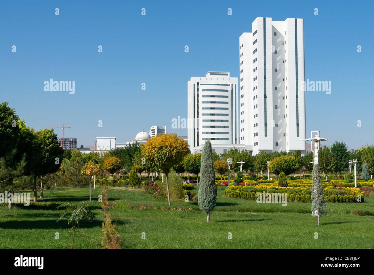 Park mit schönen Garten und Vegetation in Ashgabat, Turkmenistan. Weiße Marmorstadt. Gebäude der turkmenischen Regierungsministerien. Stockfoto