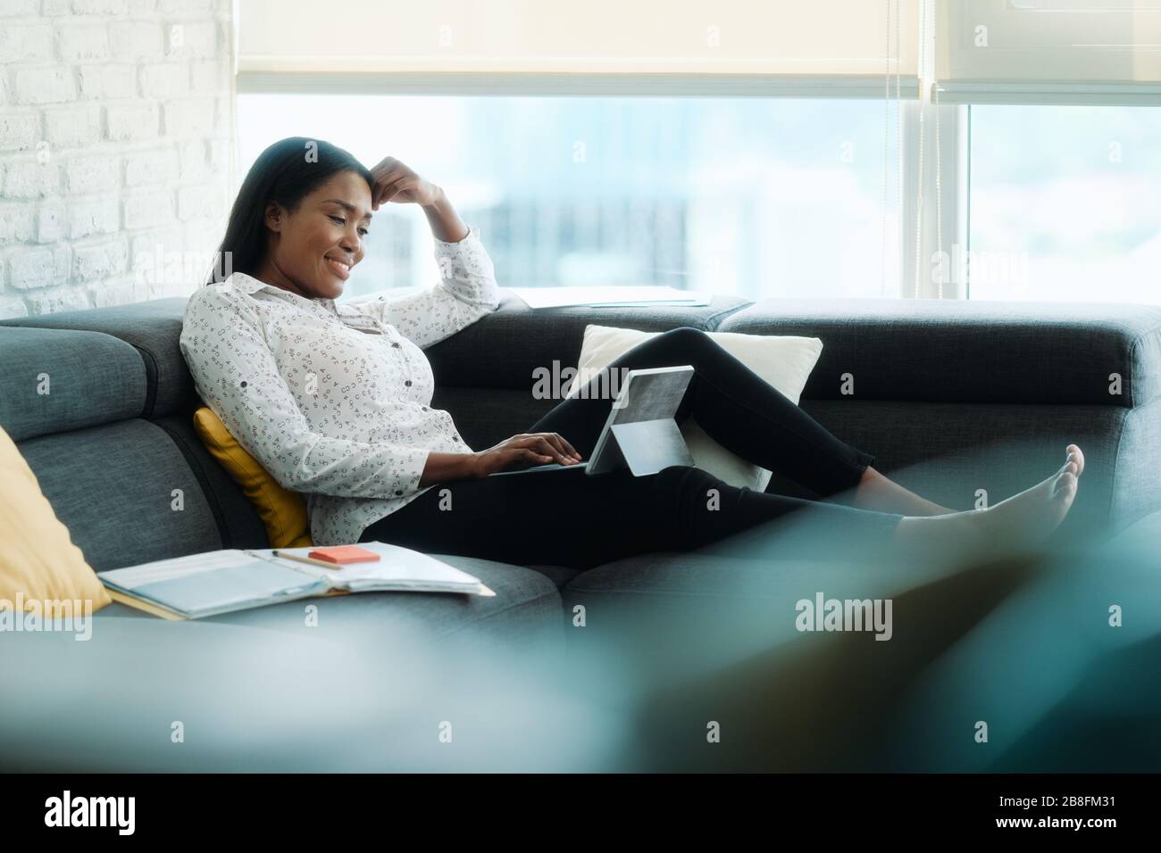 Portrait Der Geschäftsfrau, Die Auf Sofa Fernarbeitet Stockfoto