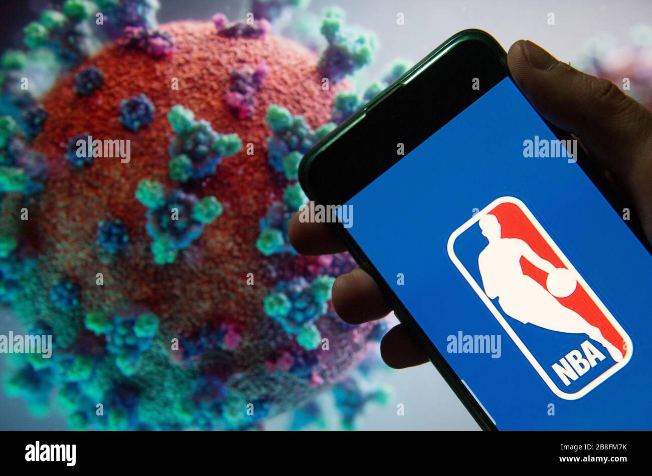 In dieser Abbildung ist das Logo der American National Basketball Association (NBA) Männer der professionellen Basketballliga auf einem Smartphone mit einem Computermodell des COVID-19 Coronavirus im Hintergrund zu sehen. Stockfoto