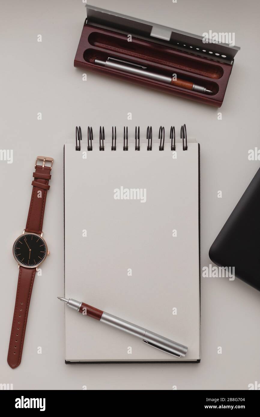 Minimalistischer Hintergrund am Arbeitsplatz mit Laptop, Stift, Stifttasche, Armbanduhr und Notebook. Weißer Büroschreibtischrahmen. Arbeiten, Geschäft, freiberufliches Konzept. C Stockfoto