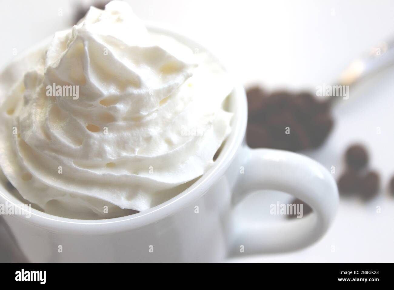 Nahaufnahme von Espresso mit Schlagsahne. Im Hintergrund Kaffeekörner Stockfoto