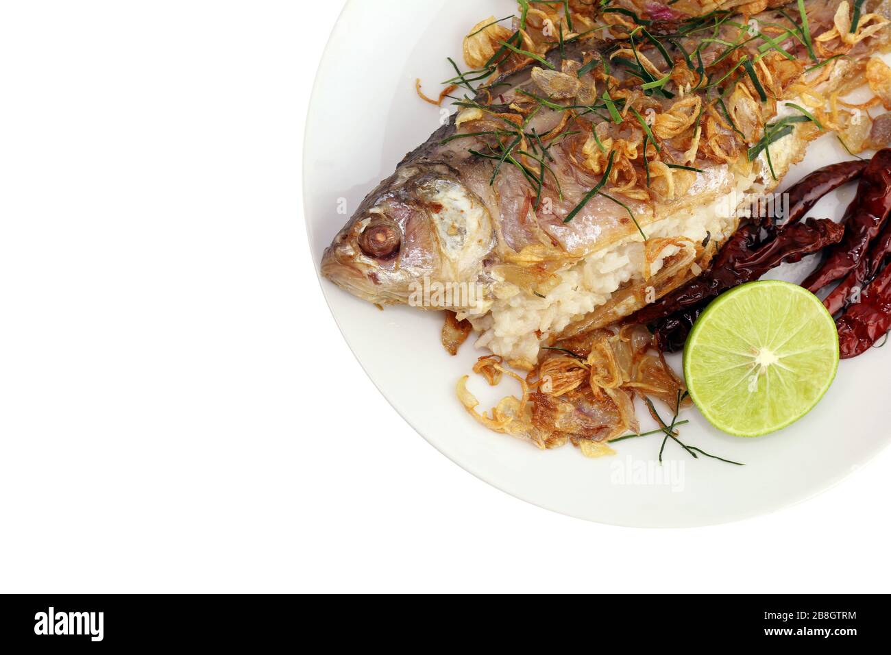 Gebackene Fische schmackhaft gebraten (Pla som tod: thailändisches Wort), gebackene Fischbraten und gebratene Zwiebeln, Limettenscheibe und gebratene Chili mit frischem Gemüse auf Weiß serviert Stockfoto