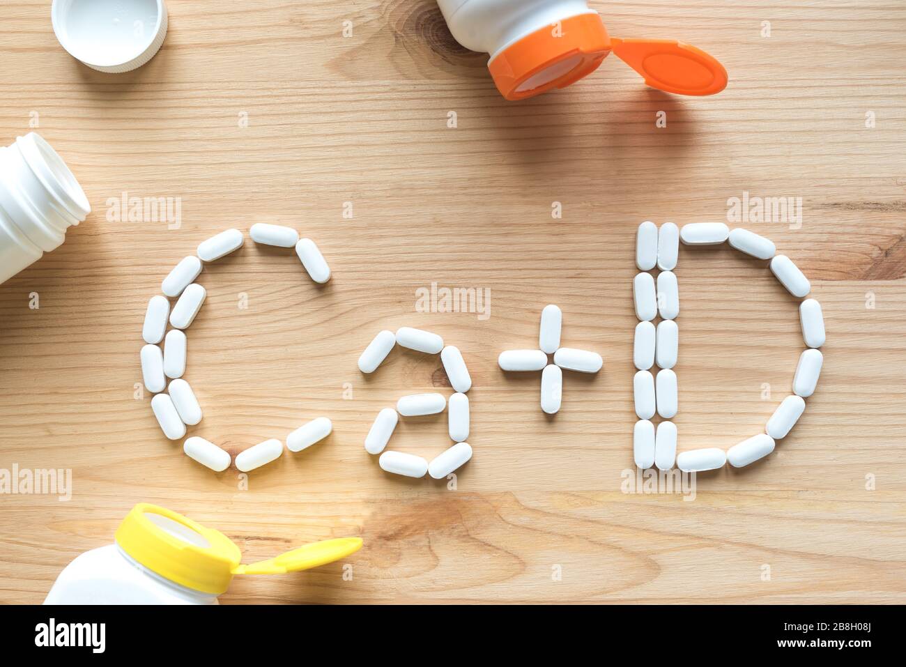Kalzium und Vitamin D Generische Tabletten. Weiße Pillen, die Form des CA+D-Alphabets auf Holzhintergrund bilden, Kopierbereich, Draufsicht. Stockfoto